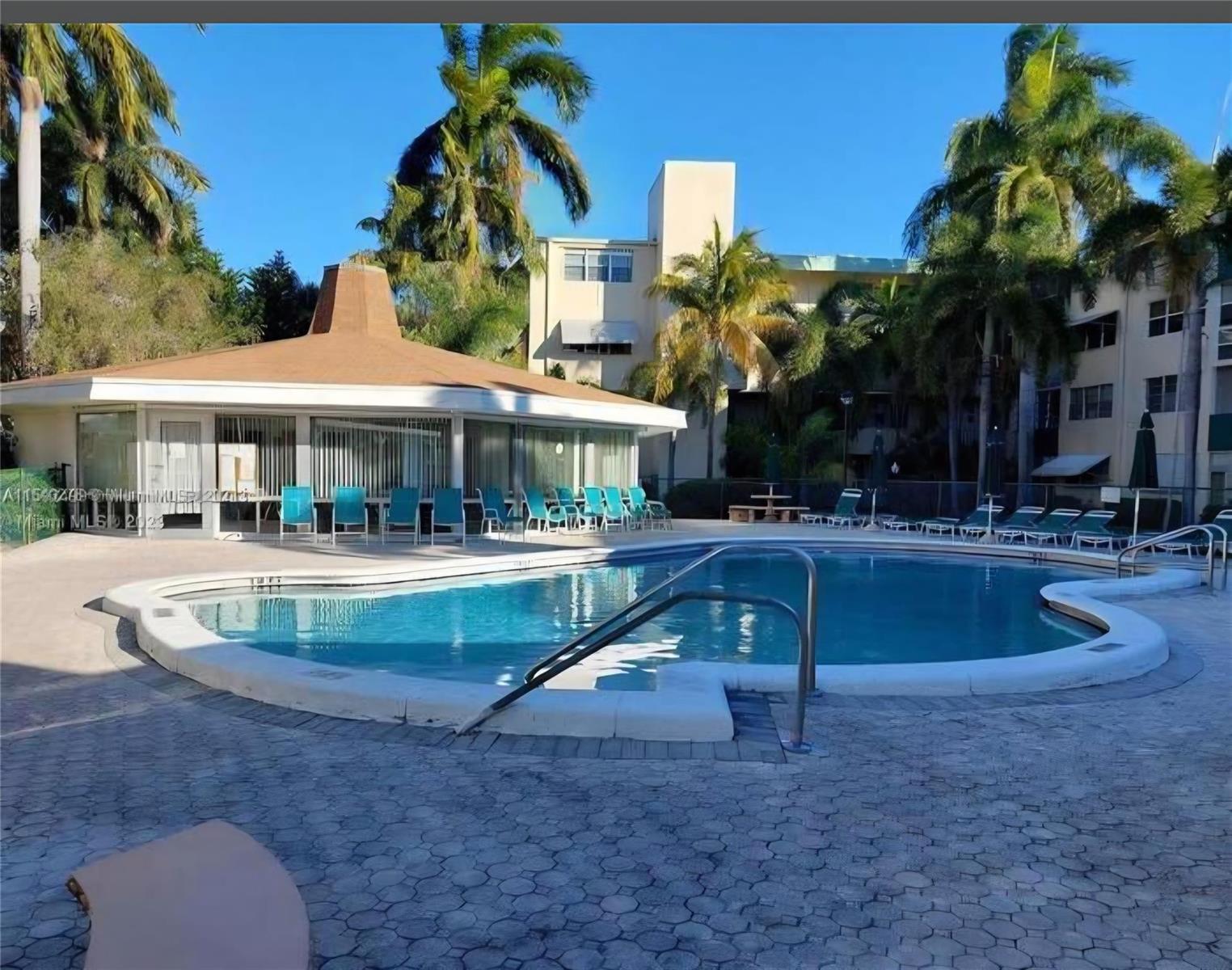 A swimming pool with a metal handrail sits in front of a circular clubhouse building — 1333 E Hallandale Beach Boulevard # 305, Hallandale Beach FL 33009, HALLANDALE BEACH, FL