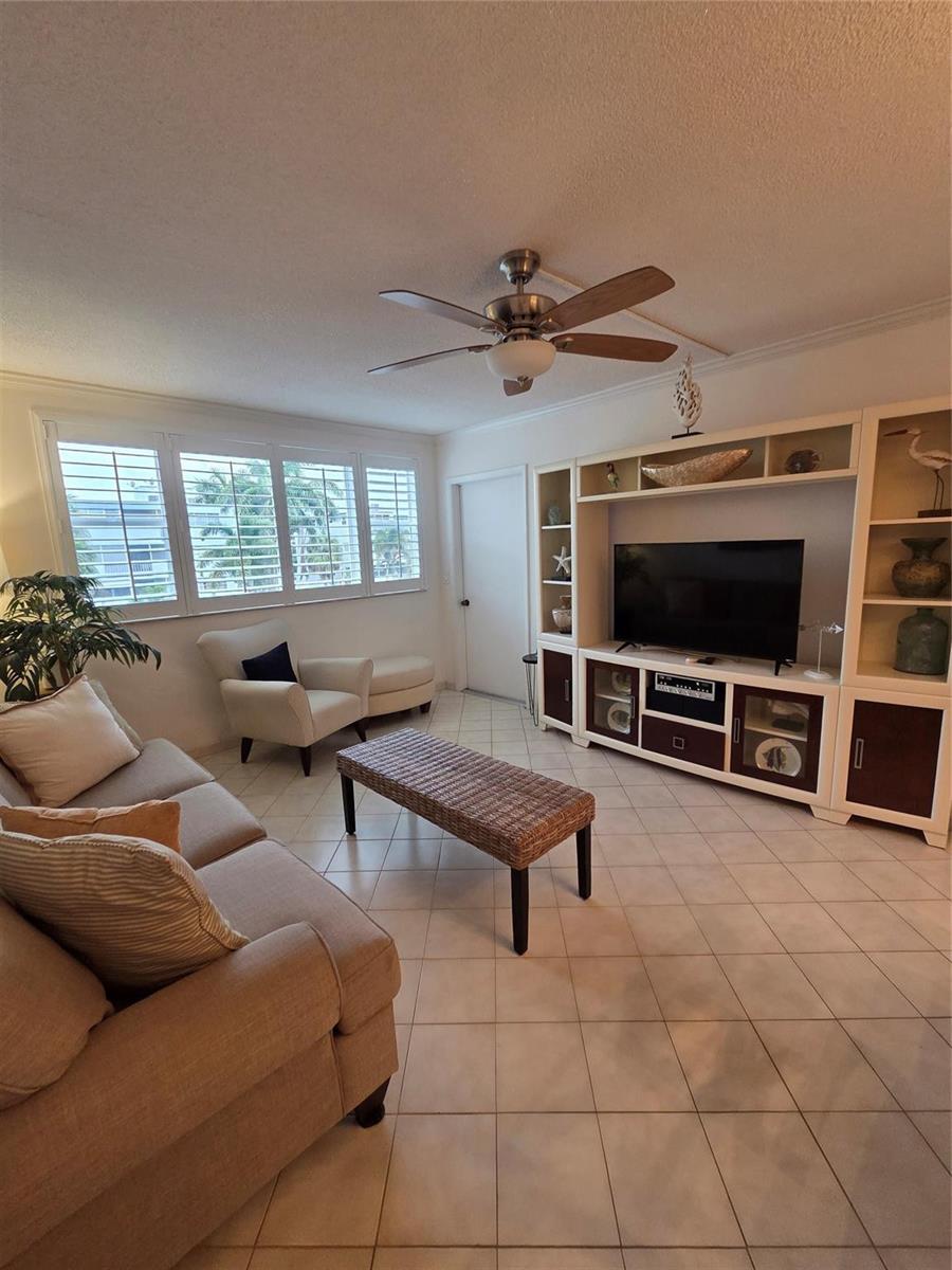 A living room features a beige sofa, wicker coffee table, and a large entertainment center — 1333 E Hallandale Beach Boulevard # 305, Hallandale Beach FL 33009, HALLANDALE BEACH, FL