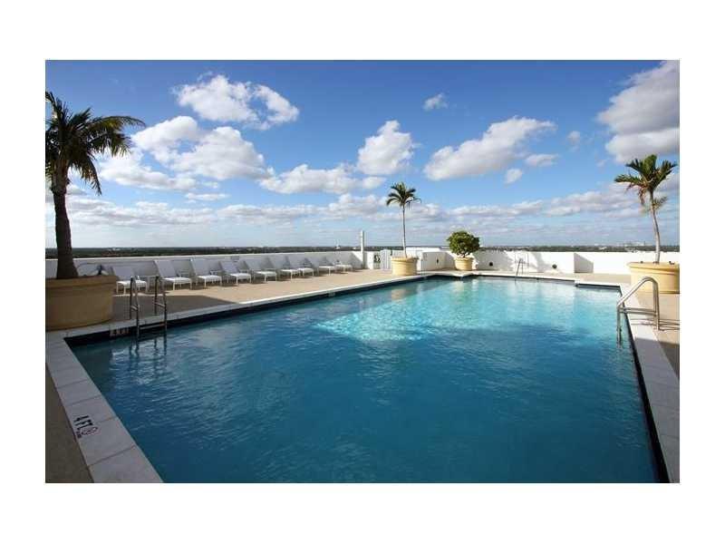 A rooftop swimming pool with lounge chairs and palm trees under a blue sky — 1830 Radius Drive # 707, Hollywood FL 33020, HOLLYWOOD, FL