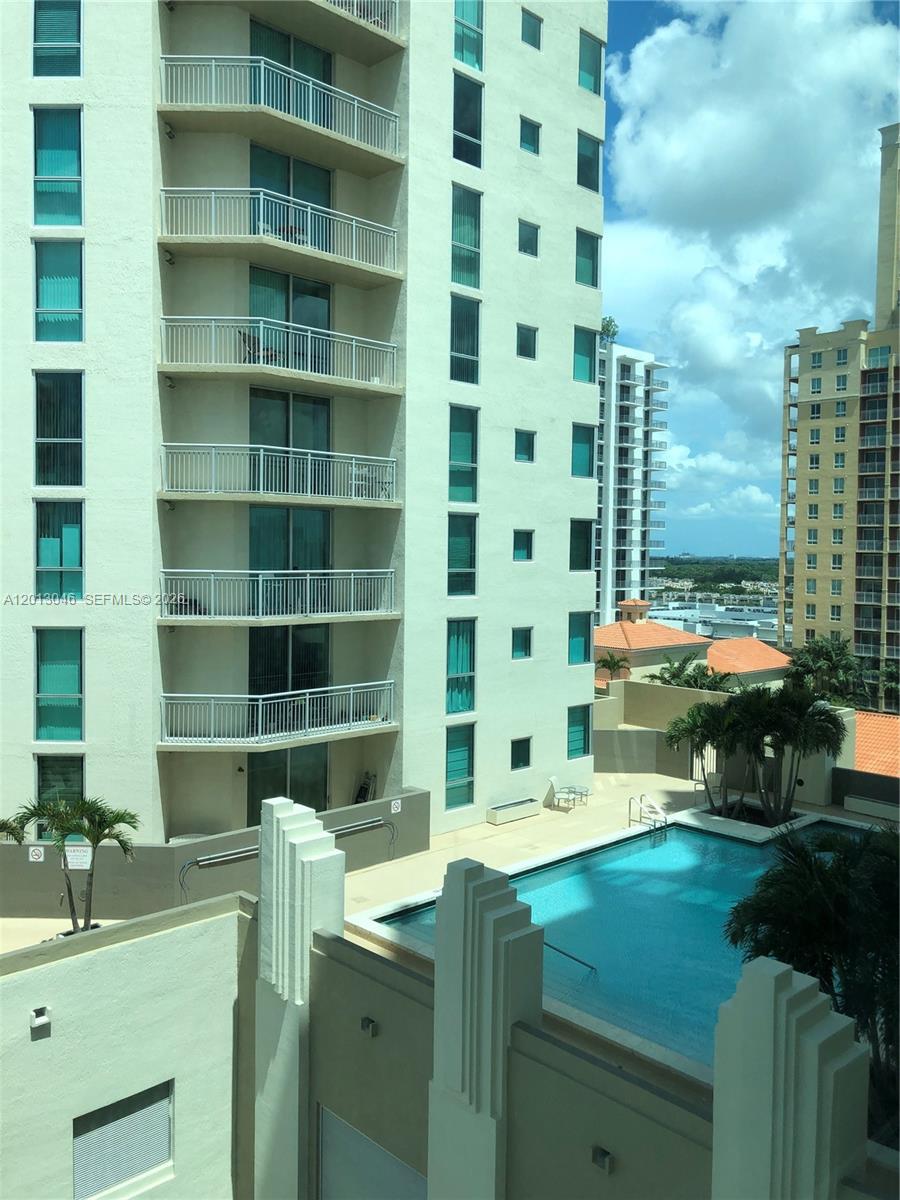 An exterior view of a high-rise apartment building with balconies overlooking a swimming pool — 9055 SW 73rd Ct # 1008, Miami FL 33156, MIAMI, FL