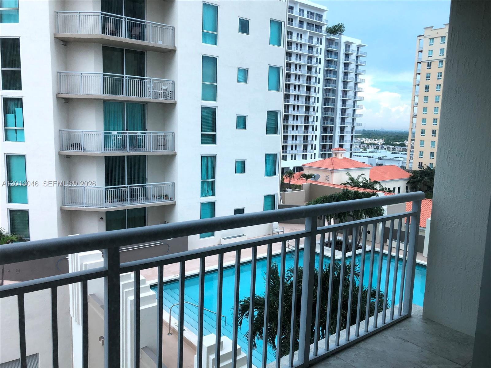 A balcony view overlooks a swimming pool surrounded by tall residential apartment buildings — 9055 SW 73rd Ct # 1008, Miami FL 33156, MIAMI, FL