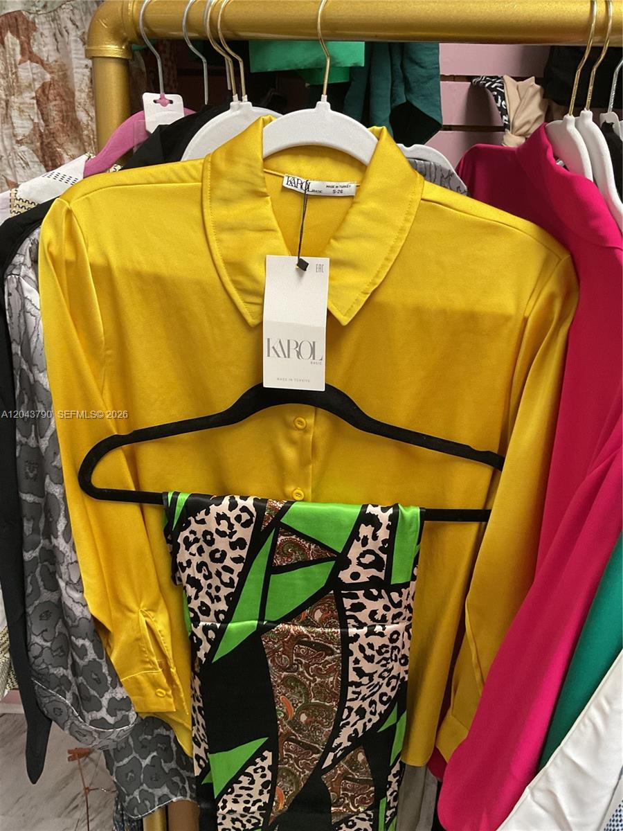 A yellow collared shirt hangs on a black hanger in front of other clothing items — 11865 SW 26th St Unit 43-27, Miami FL 33175, MIAMI, FL