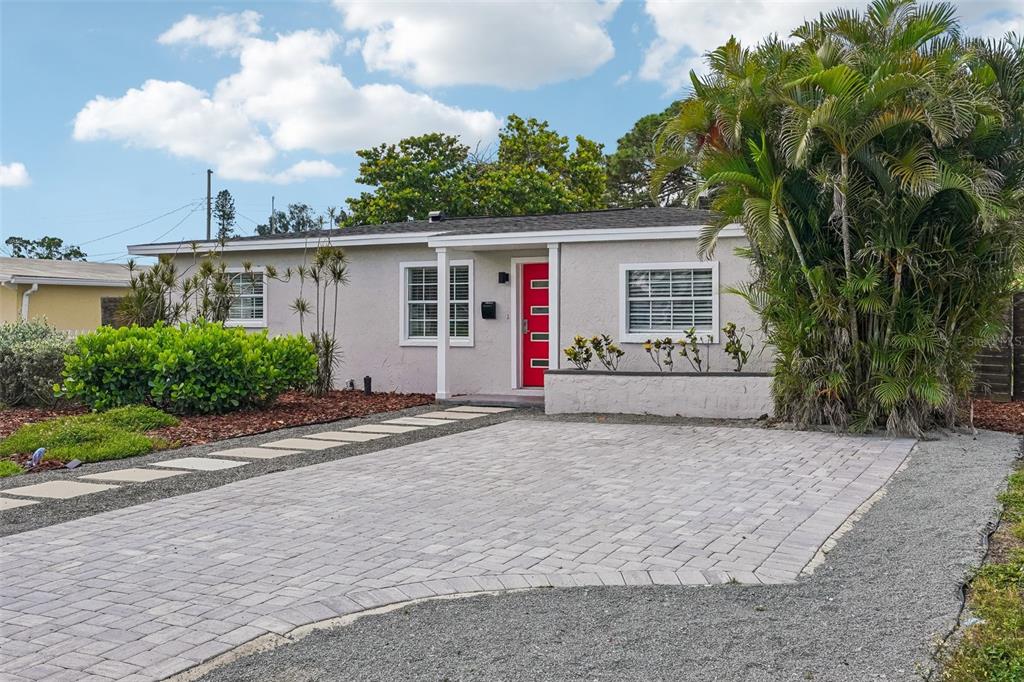 A single-story house with a red front door, paved driveway, and palm tree — 784 87TH AVENUE N, ST PETERSBURG, FL
