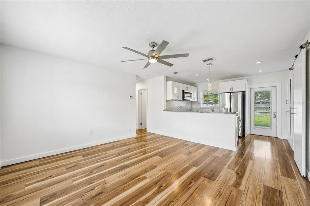 An open-concept living area features hardwood floors, a ceiling fan, and a kitchen with white cabinets — 784 87TH AVENUE N, ST PETERSBURG, FL