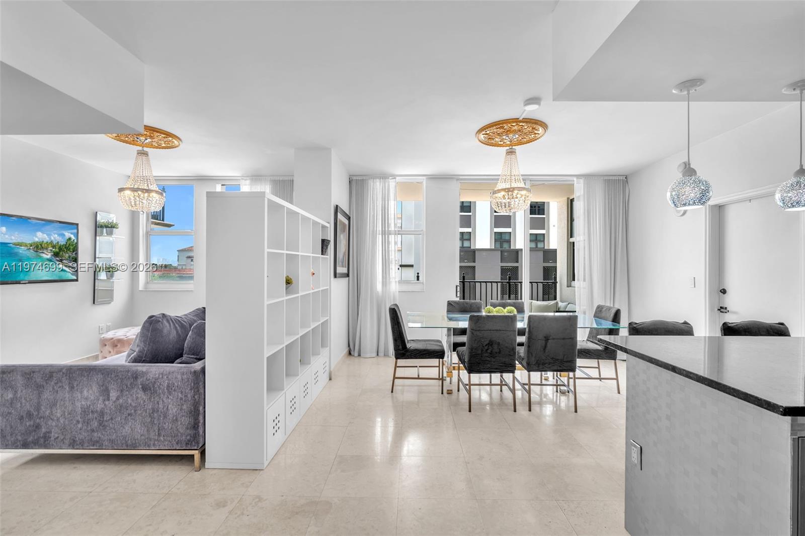 A bright living and dining area features white tile floors, a room divider, and chandeliers — 4100 Salzedo St # 519, Coral Gables FL 33146, CORAL GABLES, FL