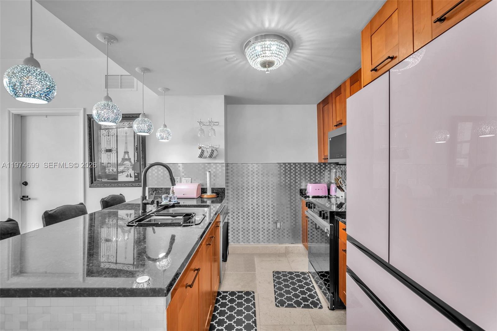 A kitchen features wooden cabinets, a dark granite island, and a metallic tiled backsplash — 4100 Salzedo St # 519, Coral Gables FL 33146, CORAL GABLES, FL