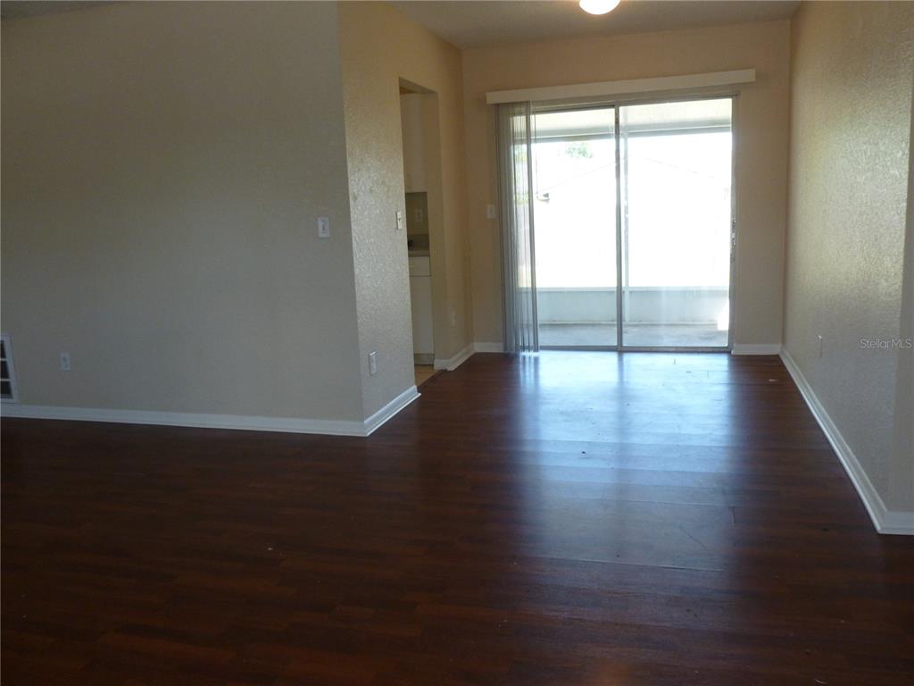 An interior view of a room with dark wood-look flooring and a sliding glass door — 5330 SPRINGWOOD ROAD, SPRING HILL, FL