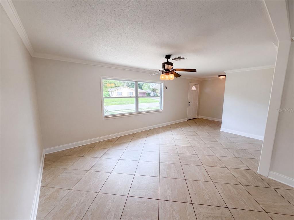 An empty living room features light-colored tile flooring, a ceiling fan, and a large window — 2223 CONIFER AVENUE, WINTER PARK, FL