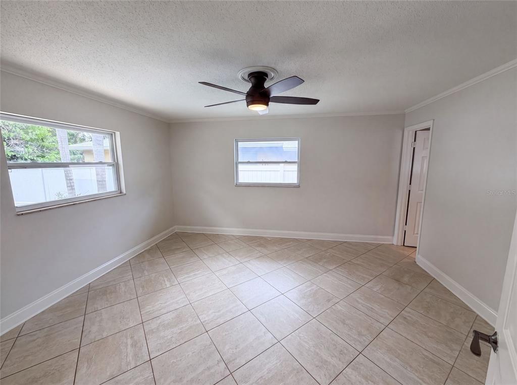 An empty room features light-colored tile flooring, white walls, a ceiling fan, and two windows — 2223 CONIFER AVENUE, WINTER PARK, FL