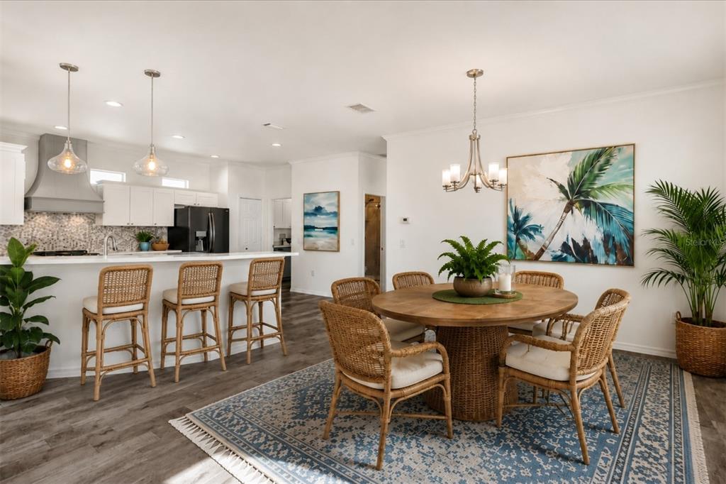 A dining area with a round wooden table and rattan chairs sits beside a kitchen — 21054 DIAMONTE DR, LAND O LAKES, FL