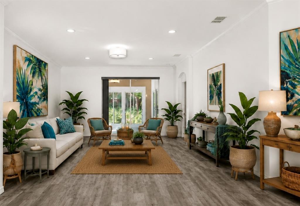 A bright living room features a white sofa, wooden coffee table, and tropical-themed wall art — 21054 DIAMONTE DR, LAND O LAKES, FL