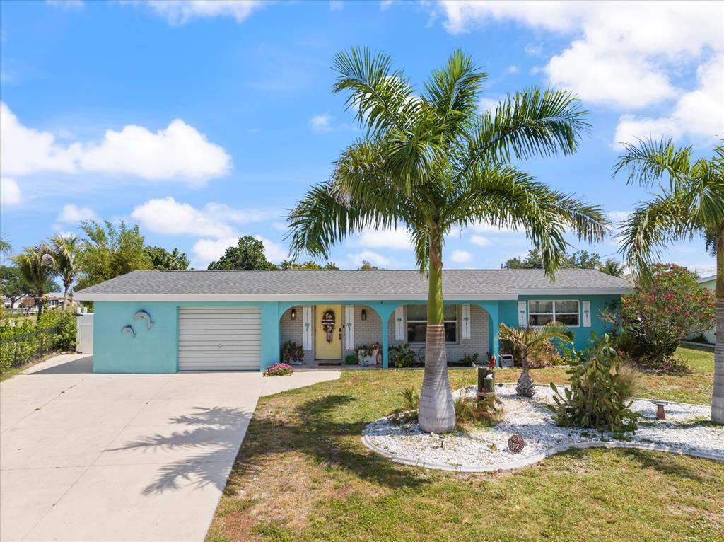 A turquoise single-story house features a palm tree in the front yard and a driveway — 168 BUCKEYE AVENUE NW, PORT CHARLOTTE, FL