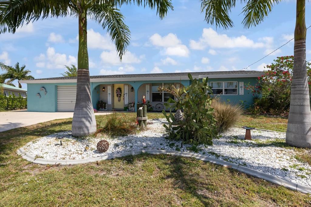 A single-story teal house with a yellow front door and a white rock garden — 168 BUCKEYE AVENUE NW, PORT CHARLOTTE, FL