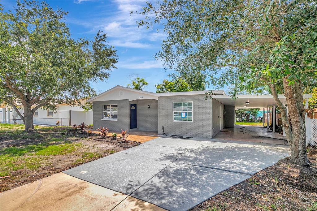 A single-story gray brick house features a concrete driveway and a covered side carport — 4845 SAN PABLO PLACE, TAMPA, FL