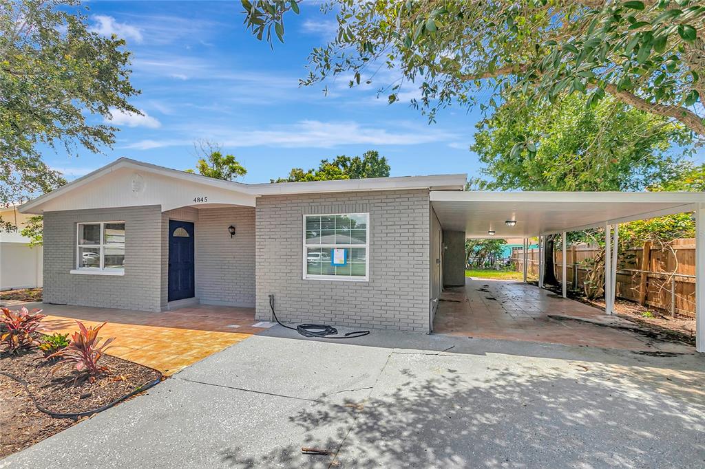A gray brick house features a front porch, a carport, and a tiled walkway — 4845 SAN PABLO PLACE, TAMPA, FL
