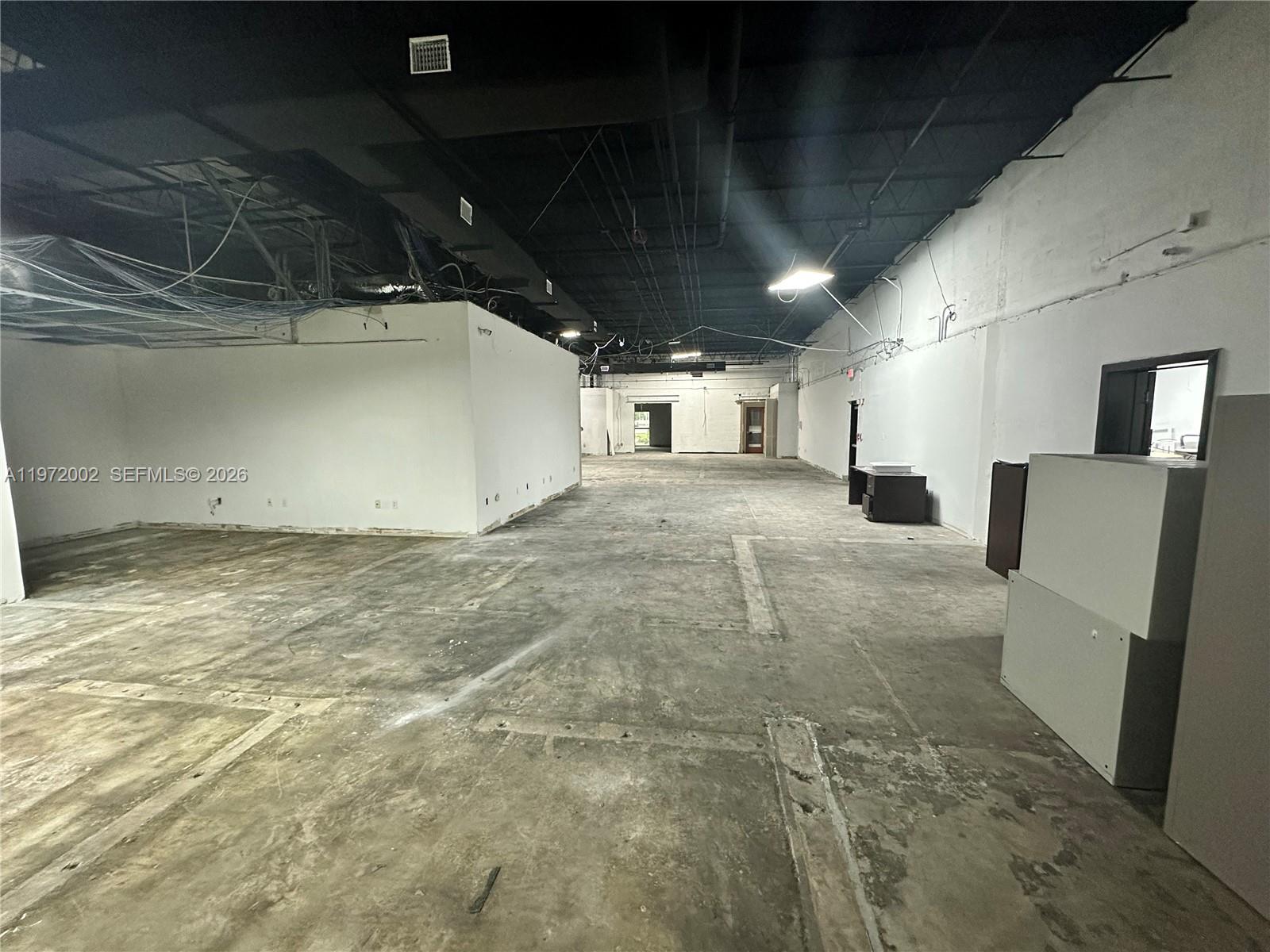 An empty commercial space features a concrete floor, white walls, and an exposed black ceiling — 2950 N 28th Ter, Hollywood FL 33020, HOLLYWOOD, FL