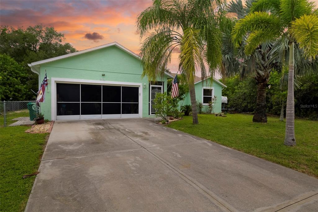 A light green house with a screened garage door and a concrete driveway — 7021 FANCY STREET, ENGLEWOOD, FL