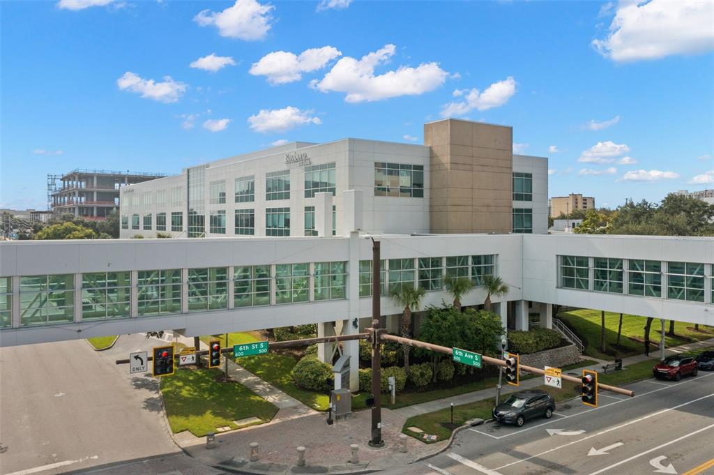 An elevated pedestrian walkway connects two modern office buildings over a street intersection — 625 6TH AVENUE S UNIT 405, ST PETERSBURG, FL