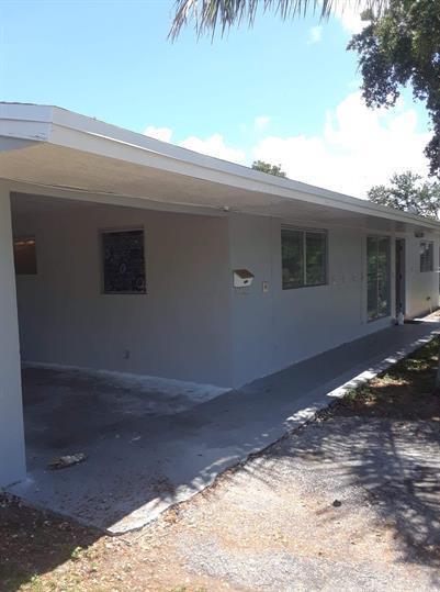 A view of the exterior of a single-story house with a carport and gray siding — 223 SE 14th Place, Deerfield Beach FL 33441, DEERFIELD BEACH, FL