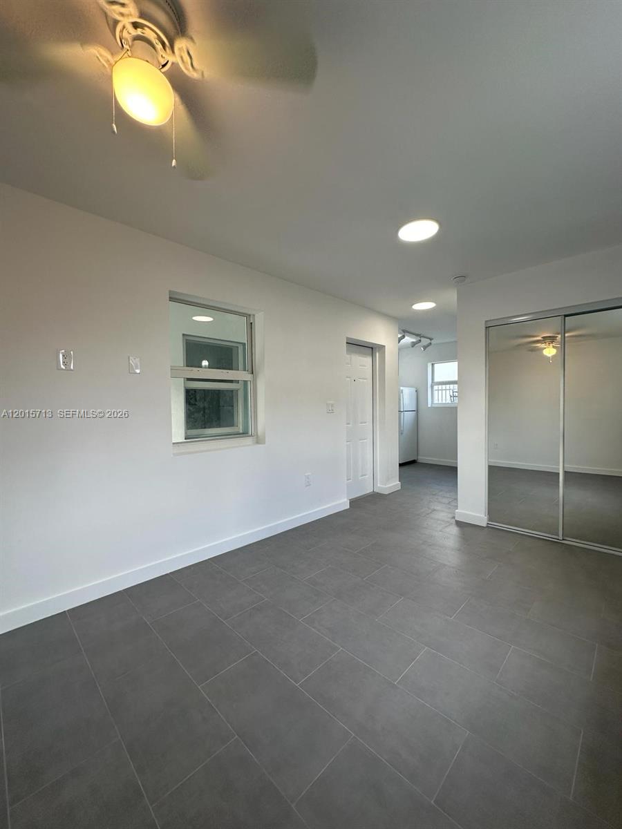 This room features gray tile flooring, white walls, a ceiling fan, and mirrored closet doors — 1535 NW 1st Pl # 10, Miami FL 33136, MIAMI, FL
