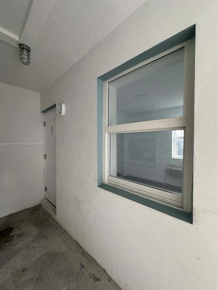 A white exterior wall features a single-hung window and a door with a light fixture — 1535 NW 1st Pl # 10, Miami FL 33136, MIAMI, FL