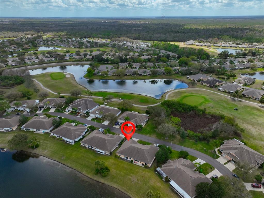 An aerial view shows a residential neighborhood with houses surrounding a golf course and lake — 2308 BROOKFIELD GREENS CIRCLE, SUN CITY CENTER, FL