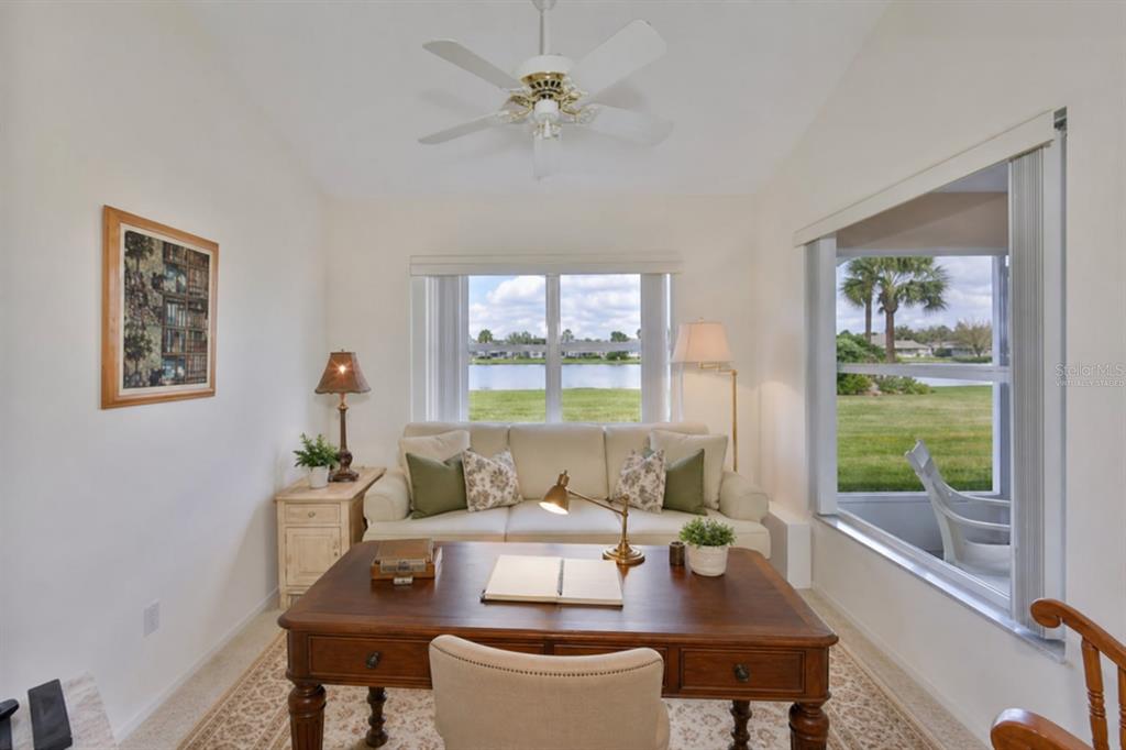 A home office features a wooden desk, a sofa, and a window view of a lake — 2308 BROOKFIELD GREENS CIRCLE, SUN CITY CENTER, FL