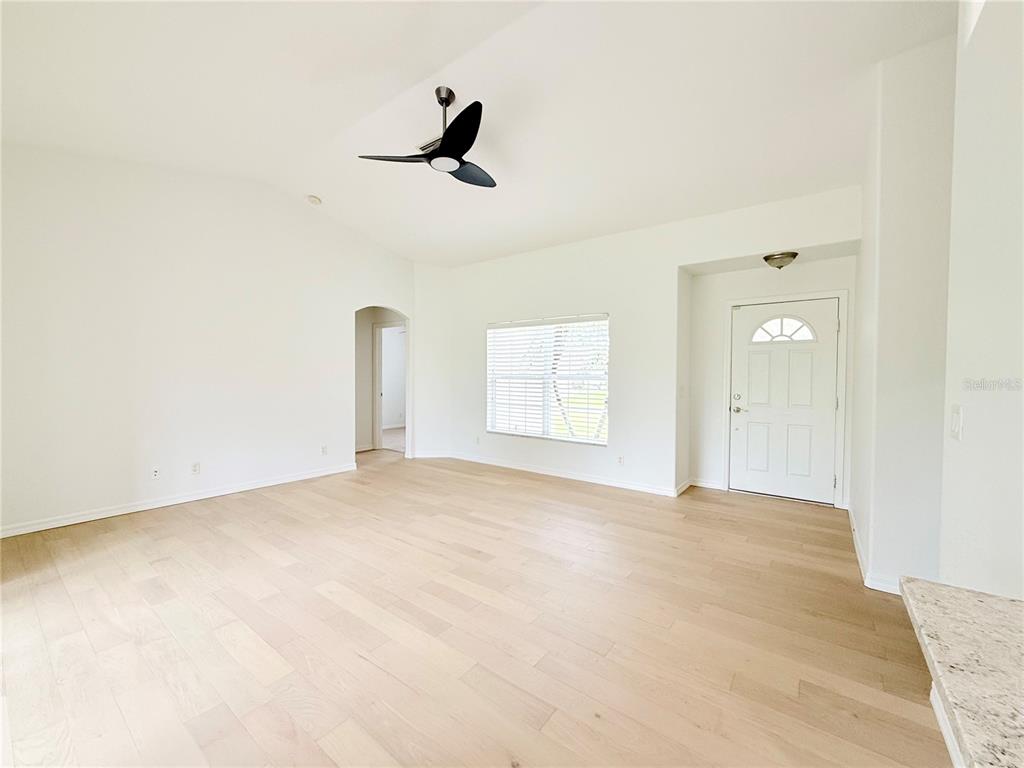 An empty living room features light wood flooring, white walls, and a ceiling fan — 4143 DANBURY TERRACE, NORTH PORT, FL