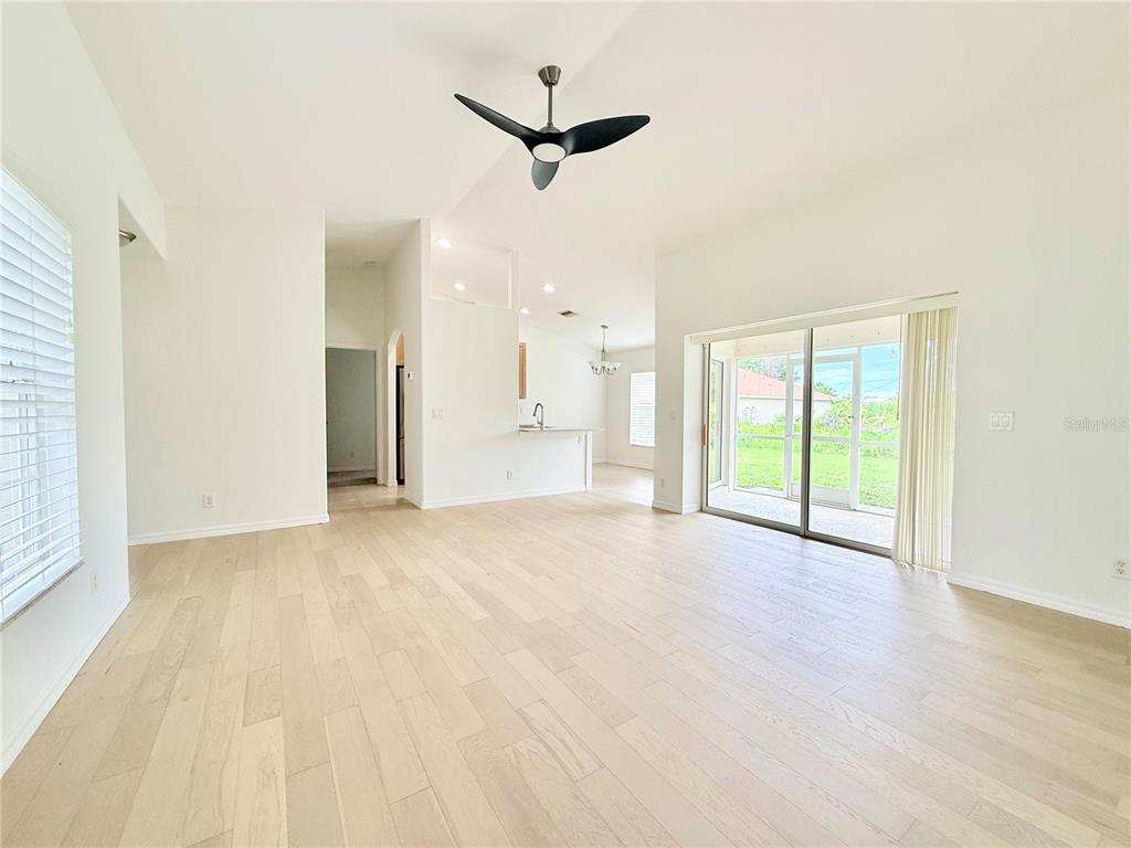 A bright living area features light wood flooring, a ceiling fan, and sliding glass doors — 4143 DANBURY TERRACE, NORTH PORT, FL