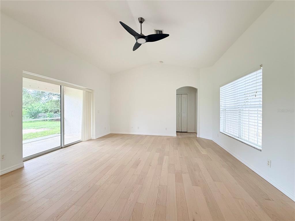 A bright living room features light wood flooring, a ceiling fan, and sliding glass doors — 4143 DANBURY TERRACE, NORTH PORT, FL