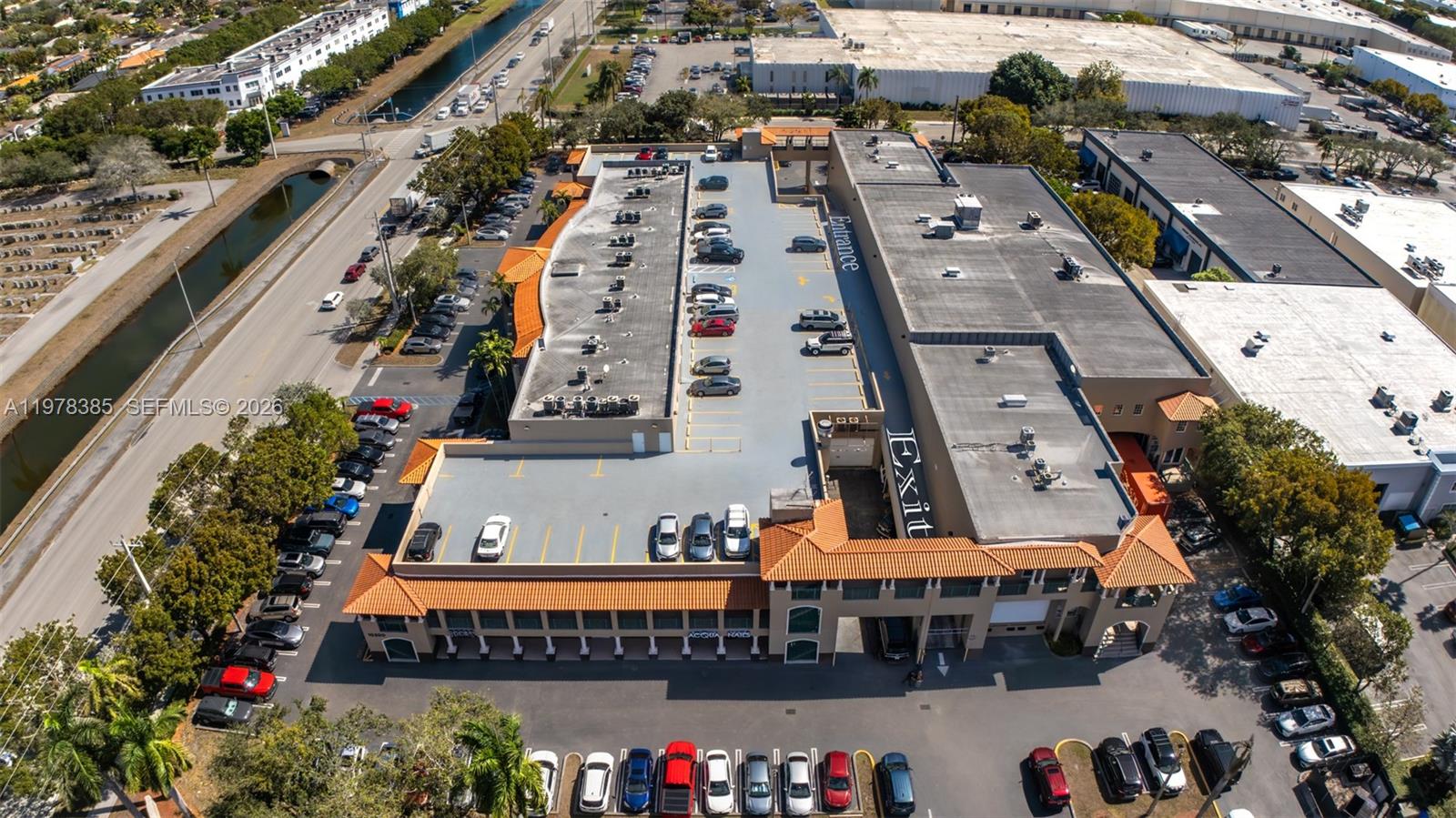 An aerial view shows a commercial building with a rooftop parking deck and surrounding lots — 10200 NW 25th St, Doral FL 33172, DORAL, FL