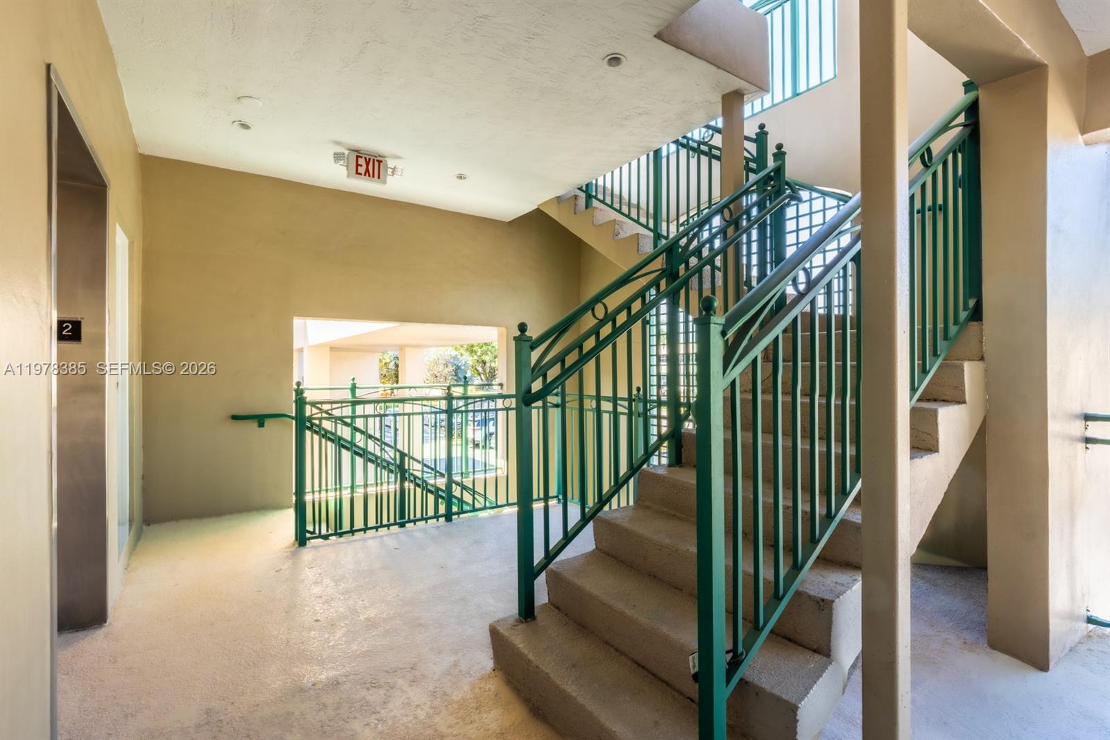 An outdoor stairwell features concrete steps, green metal railings, and an exit sign — 10200 NW 25th St, Doral FL 33172, DORAL, FL