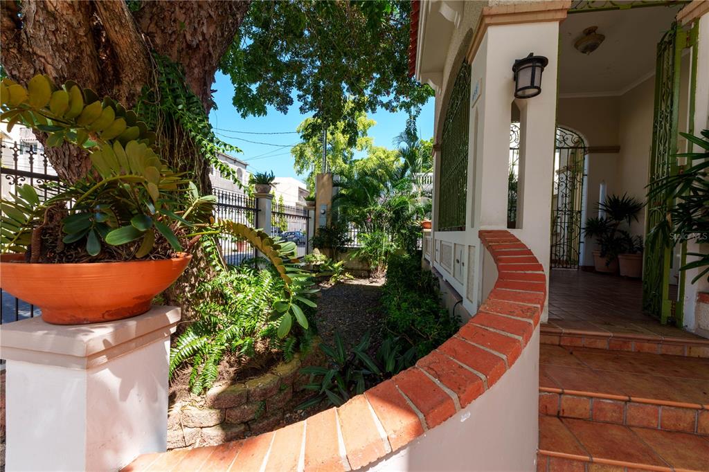 A curved brick wall leads to a covered entryway with tiled steps and potted plants — 655 CONCORDIA, SAN JUAN, PR