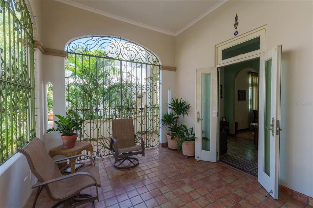 A covered patio features tiled floors, decorative metal security grilles, and glass doors leading indoors — 655 CONCORDIA, SAN JUAN, PR