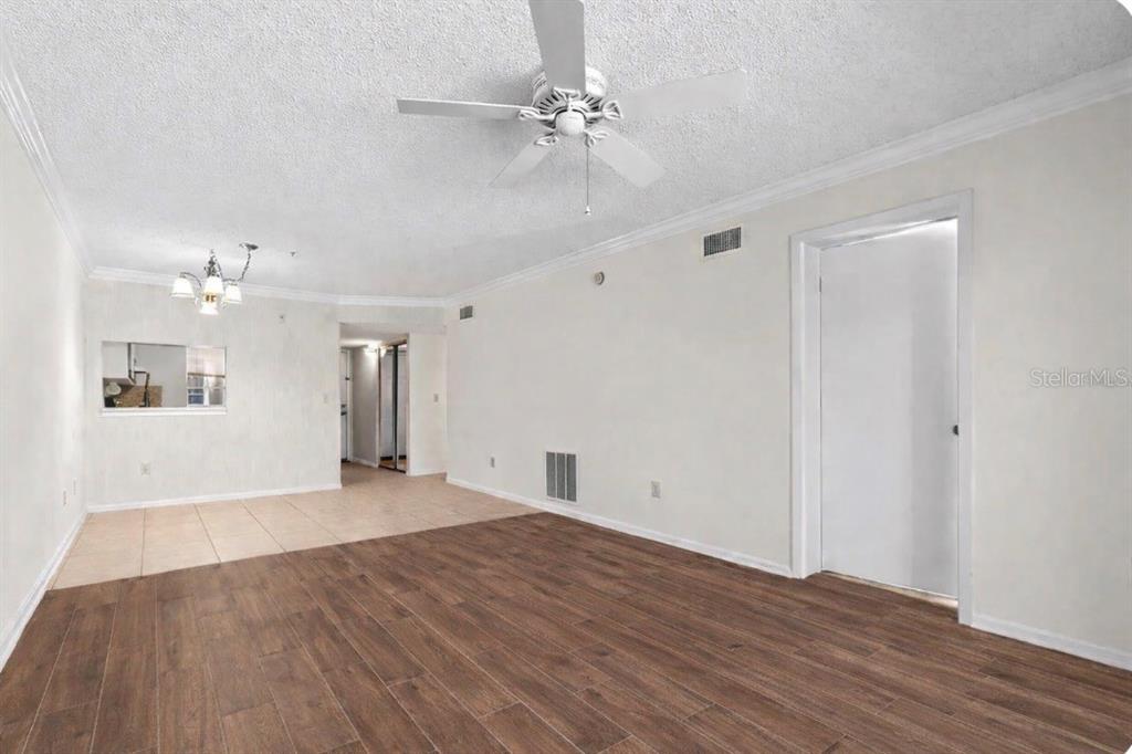 A living room features wood-look flooring, a ceiling fan, and an adjacent tiled dining area — 7294 CLOISTER DRIVE UNIT 23, SARASOTA, FL