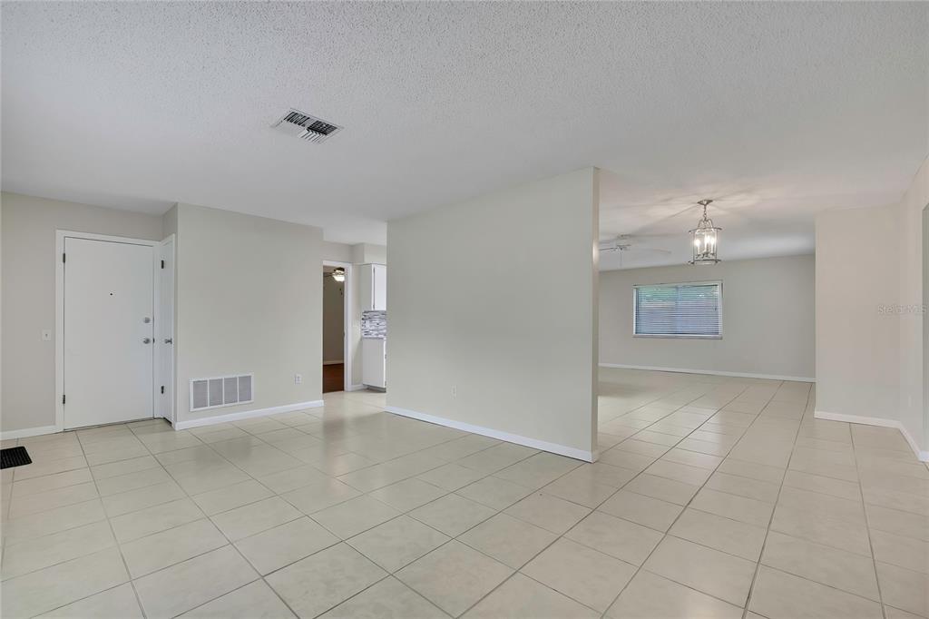An interior view of a room with light-colored tile flooring and a white partition wall — 9279 PICKENS STREET, SPRING HILL, FL