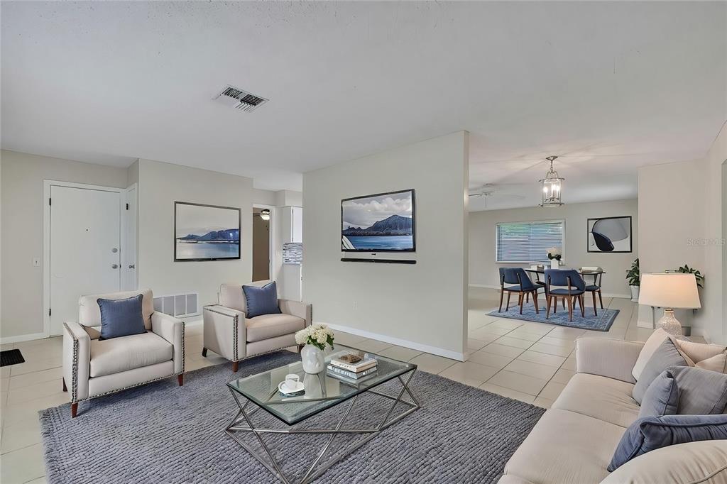 A living room with tile floors, a gray area rug, and an adjacent dining area — 9279 PICKENS STREET, SPRING HILL, FL