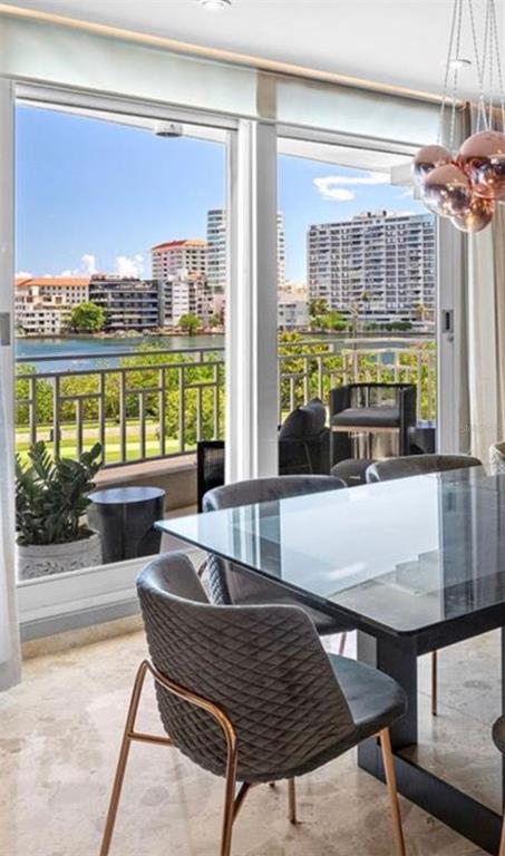 A dining room with a glass table and grey chairs overlooks a waterfront city view — 548 Hoare St. LAGUNA UNIT 3, SAN JUAN, PR