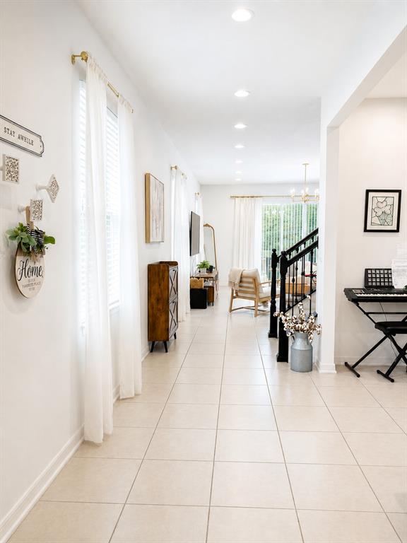 A bright, open-concept living area features tile flooring, white walls, and a staircase with black railings — 8205 BAYLISS COURT, ORLANDO, FL