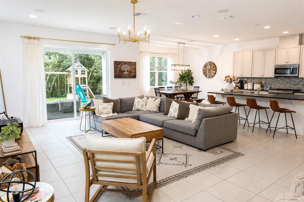 An open-concept living room and kitchen featuring a gray sectional, wooden coffee table, and patio — 8205 BAYLISS COURT, ORLANDO, FL