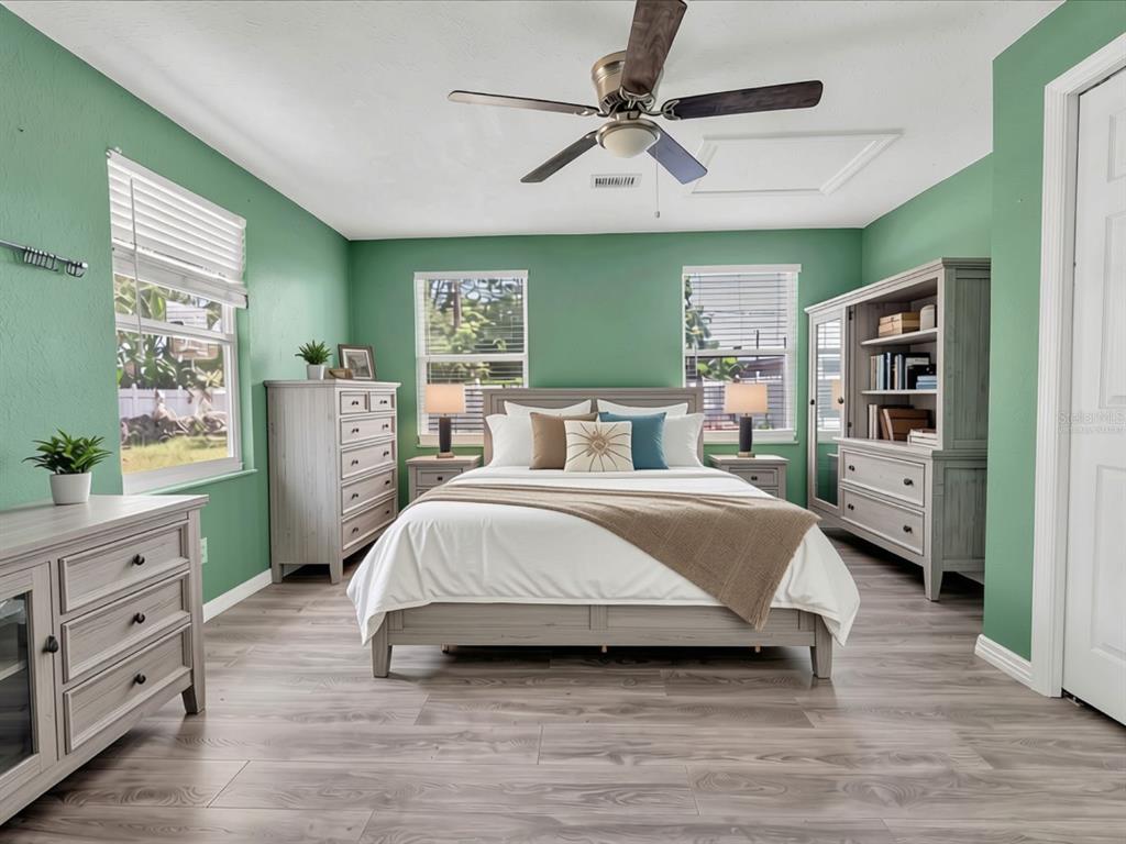 A bedroom with green walls, light wood-look flooring, a bed, and matching grey furniture — 1966 MCKINLEY STREET, CLEARWATER, FL