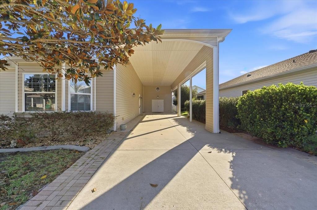 A side view of a tan vinyl-sided house with a stone accent wall and landscaping — 323 TRAVELERS DRIVE, POLK CITY, FL