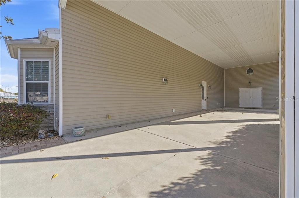 An open-concept kitchen with white cabinets and a breakfast bar overlooks a carpeted living area — 323 TRAVELERS DRIVE, POLK CITY, FL