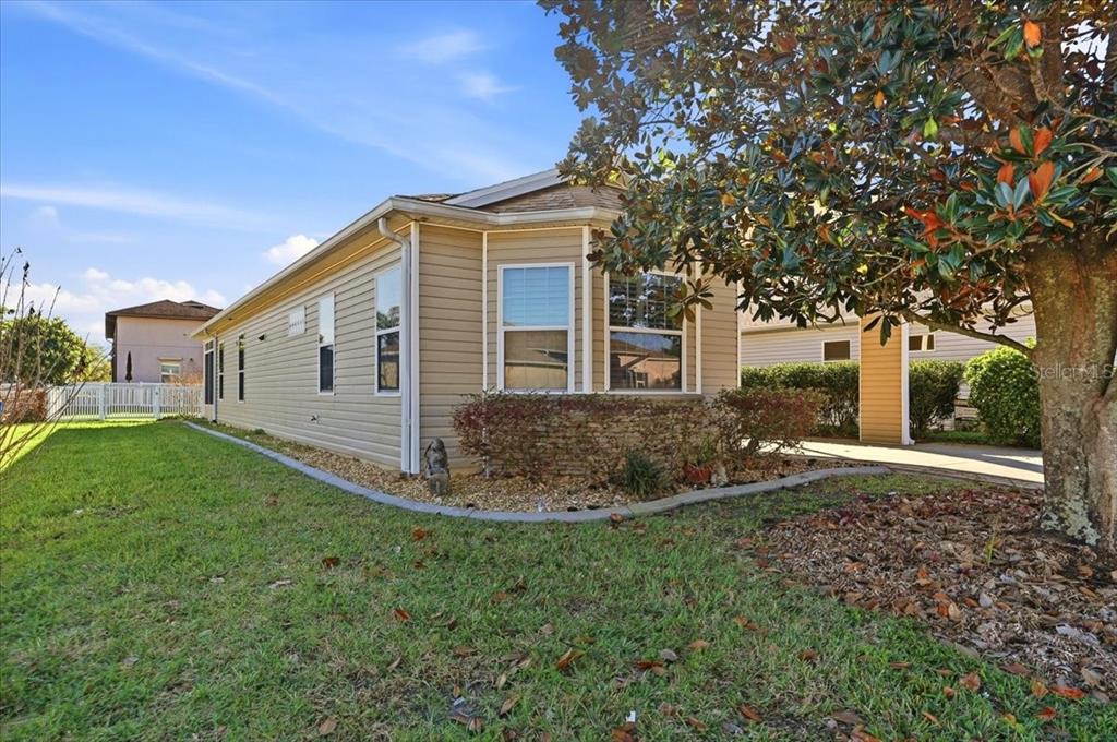 A living room with beige carpet, a ceiling fan, and an open kitchen in the background — 323 TRAVELERS DRIVE, POLK CITY, FL