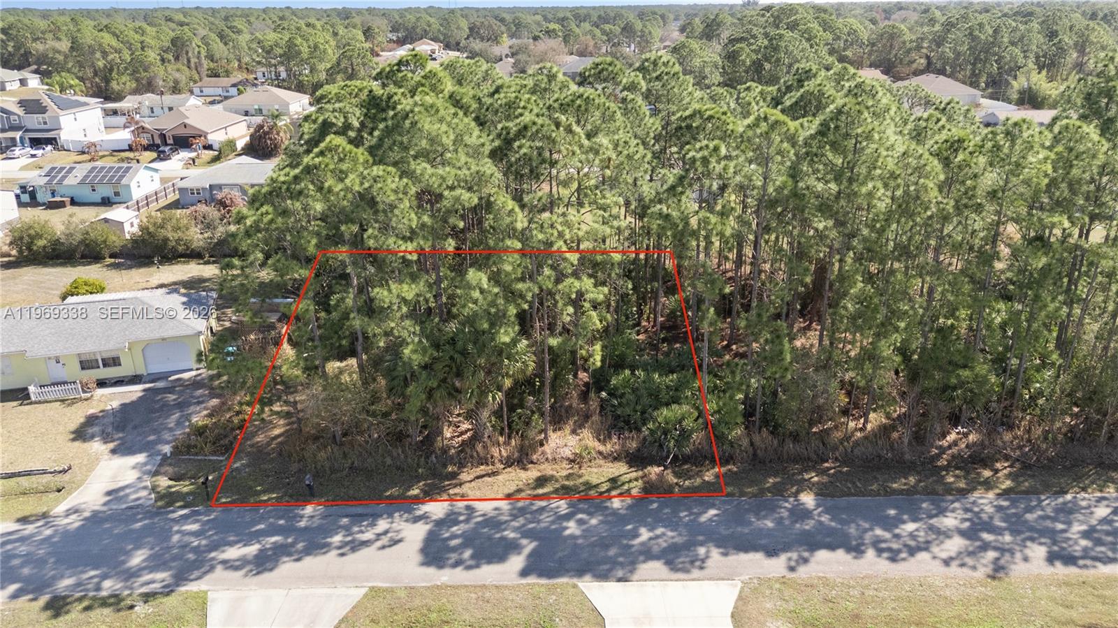 An aerial view shows a vacant, wooded residential lot outlined in red along a paved road — 971 Cranberry Rd SE, Palm Bay FL 32909, PALM BAY, FL