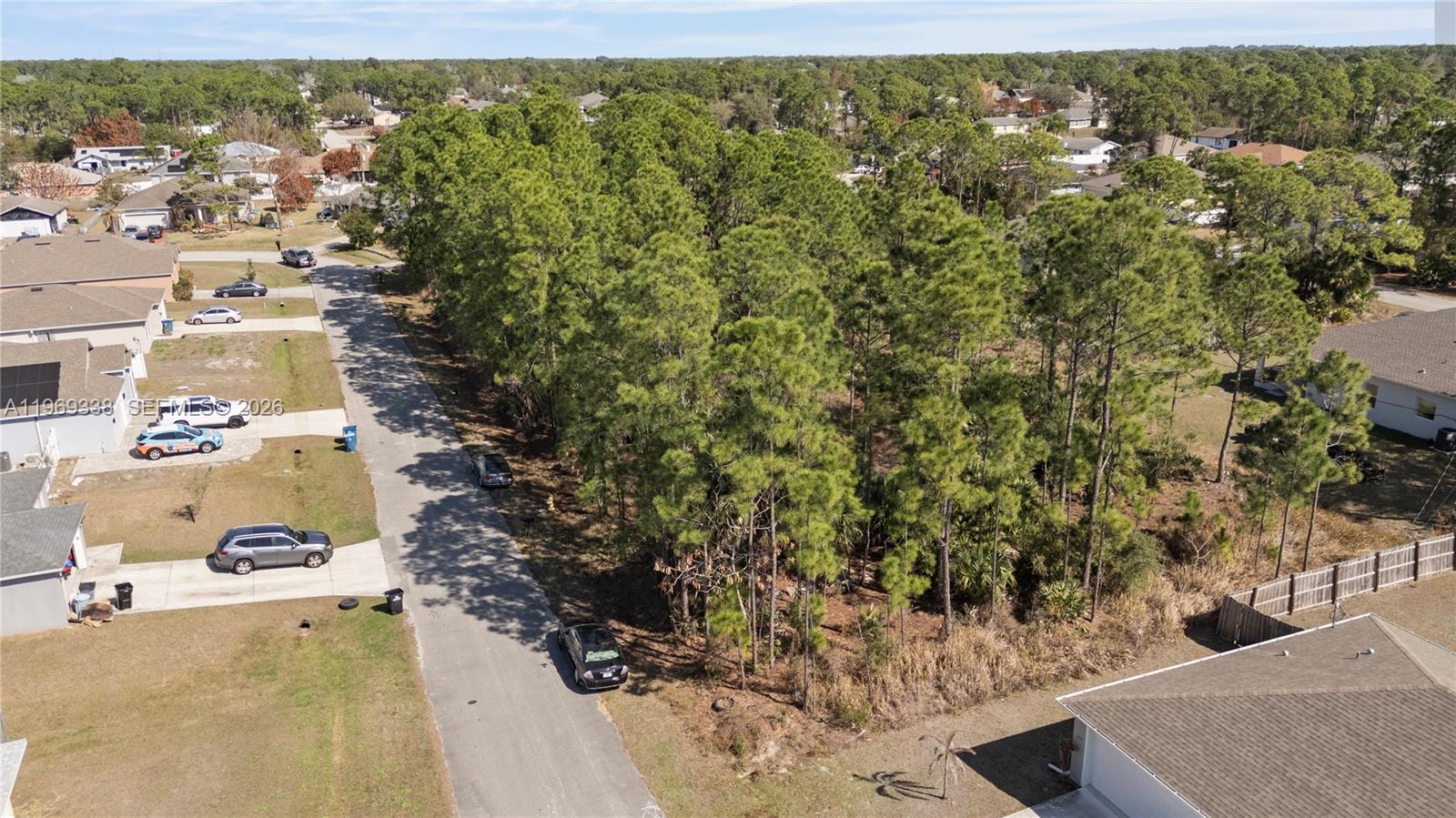 An aerial view shows a vacant wooded lot situated between two residential houses and a street — 971 Cranberry Rd SE, Palm Bay FL 32909, PALM BAY, FL