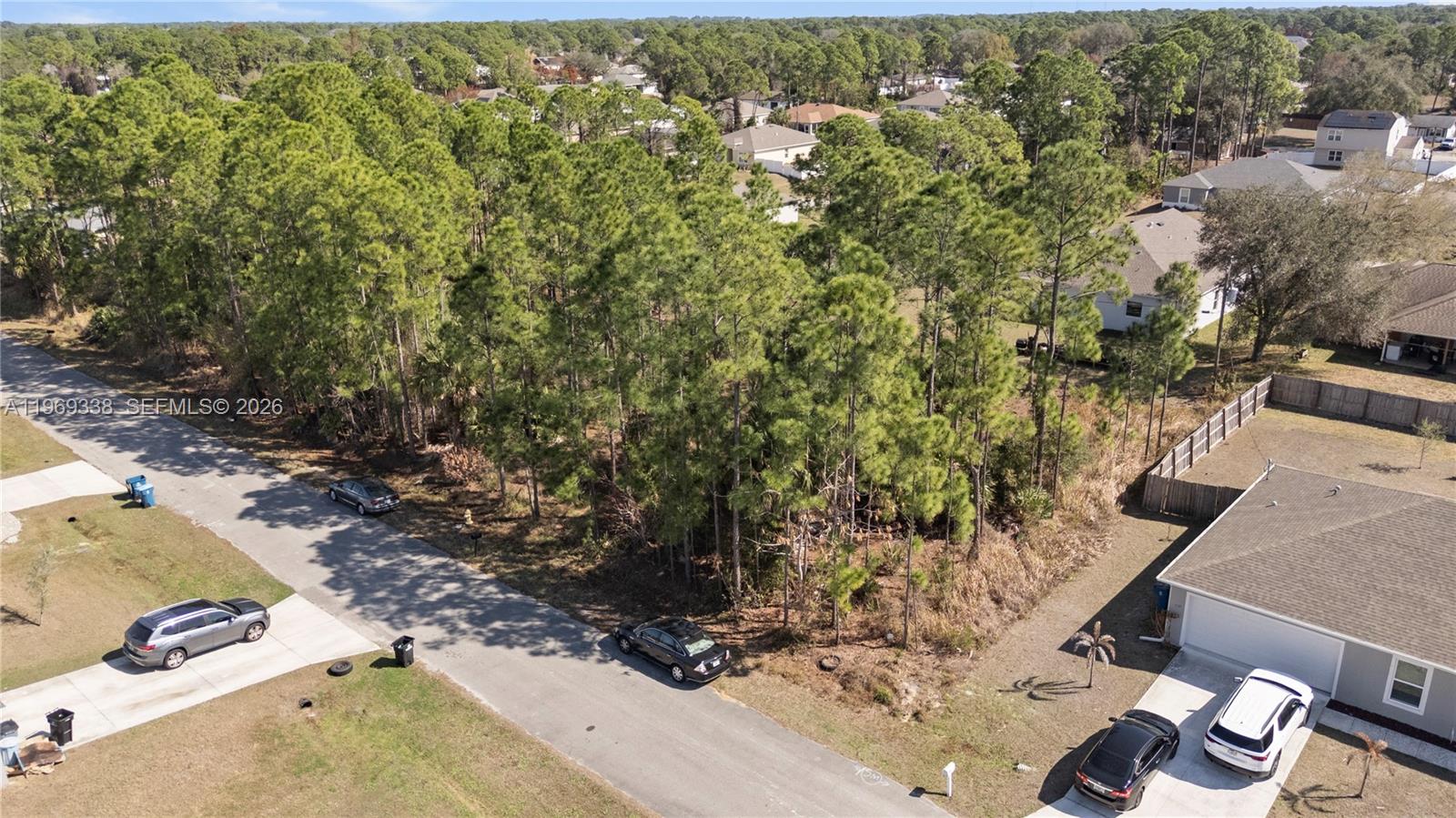 An aerial view shows a vacant, wooded residential lot situated between two suburban houses — 971 Cranberry Rd SE, Palm Bay FL 32909, PALM BAY, FL