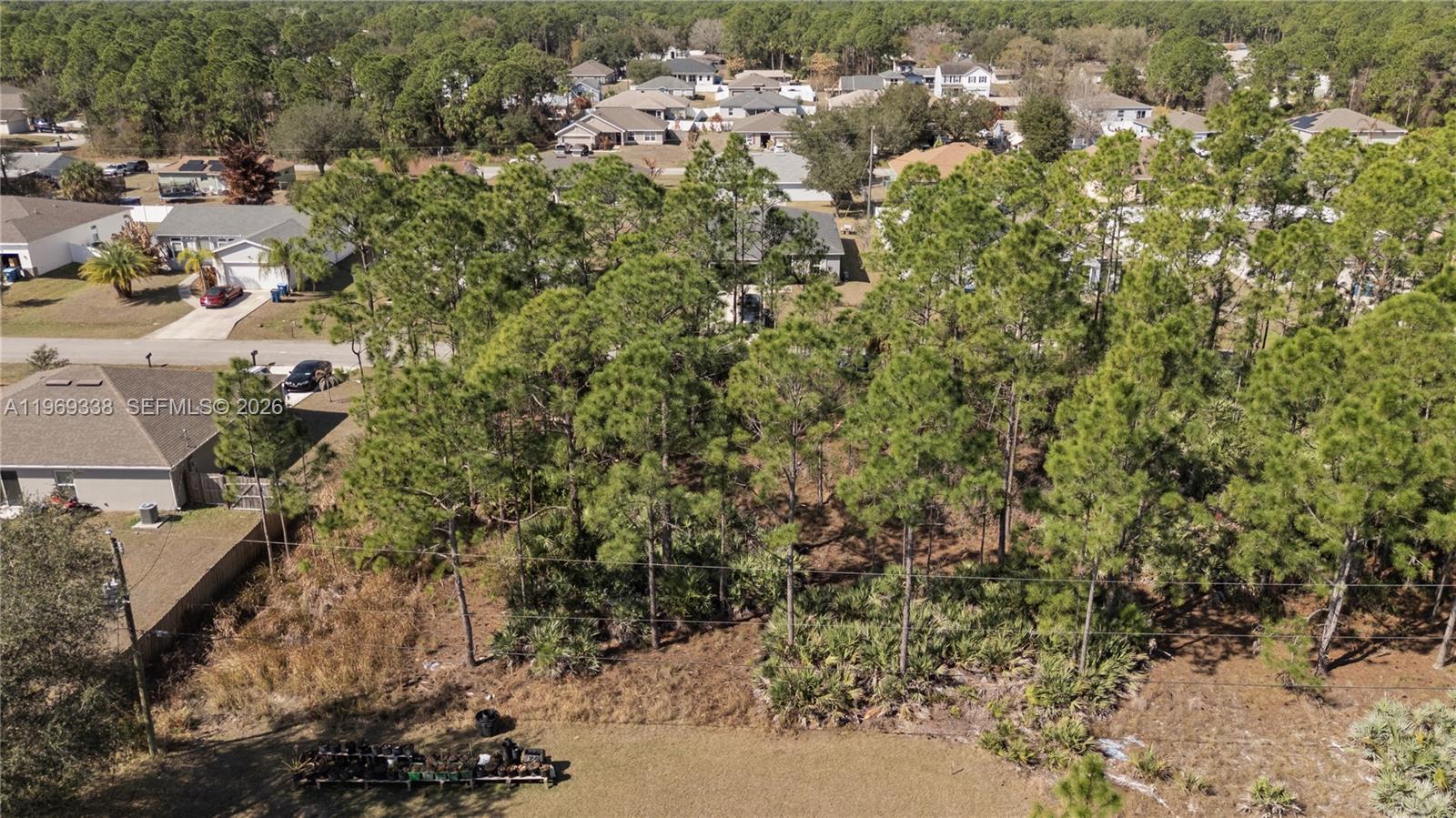 An aerial view shows a wooded residential lot situated between suburban houses and streets — 971 Cranberry Rd SE, Palm Bay FL 32909, PALM BAY, FL