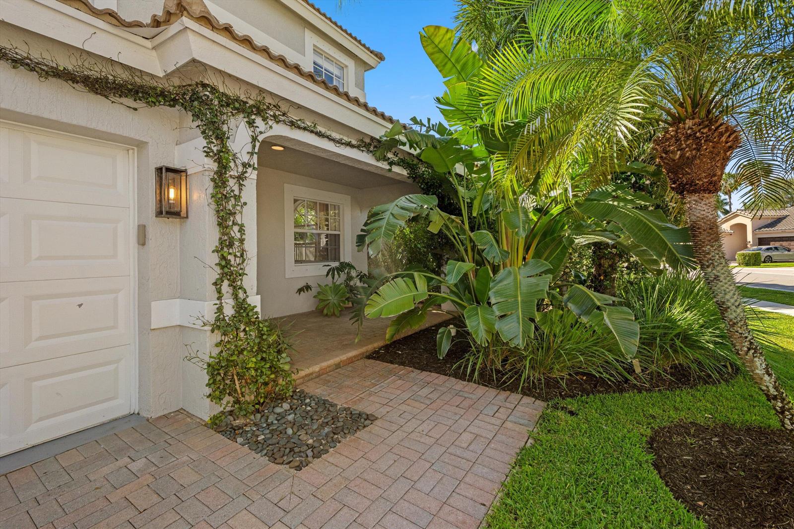 A paved walkway leads to the covered entryway of a house with a garage and landscaping — 4138 Bluff Harbor Way, Wellington FL 33449, WELLINGTON, FL