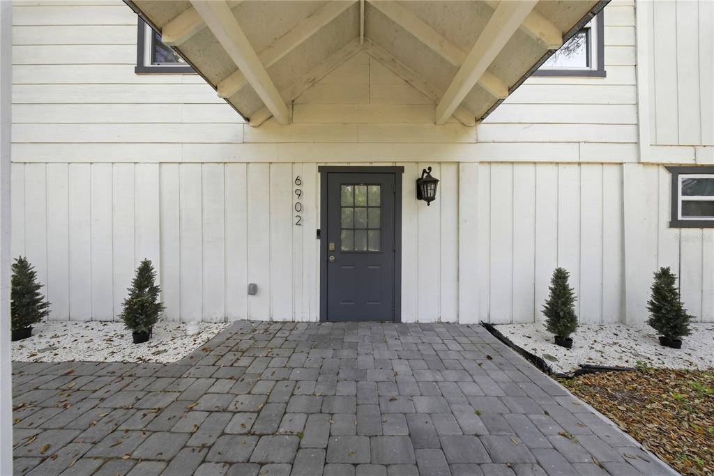 A gray front door with a house number sits under a covered entryway — 6902 E 29TH AVENUE, TAMPA, FL